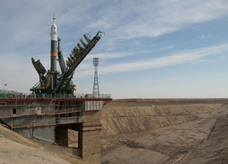 Large gantry mechanisms on either side of the Soyuz TMA-08M spacecraft are raised into position to secure the rocket at the launch pad on Tuesday at the Baikonur Cosmodrome in Kazakhstan.