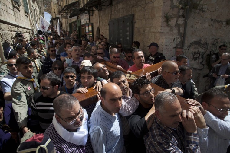 Christian worshippers carry a cross towards the Church of the Holy Sepulcher, traditionally believed by many to be the site of the crucifixion of Jesus Christ, during the Good Friday procession in Jerusalem's Old City, Friday, March 29, 2013. Less than 2 percent of the population of Israel and the Palestinian territories is Christian, mostly split between Catholicism and Orthodox streams of Christianity. Christians in the West Bank wanting to attend services in Jerusalem must obtain permission from Israeli authorities. Israel's Tourism Ministry said it expects some 150,000 visitors in Israel during Easter week and the Jewish festival of Passover, which coincide this year.