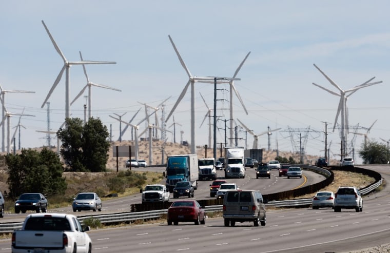 Automobiles pass by giant wind turbines powered by strong winds in Palm Springs, Calif.