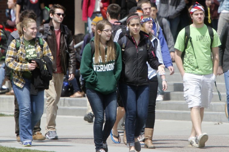 Students walk across campus at the University of Vermont in Burlington, Vt. A new report says low-income students are increasingly bypassed for merit-...