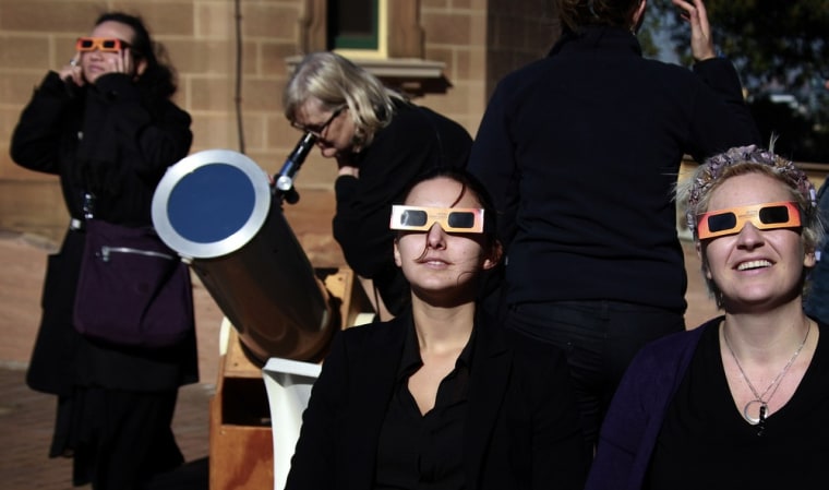 Women wear protective glasses as they gaze at Friday's solar eclipse from Sydney's Observatory Hill.