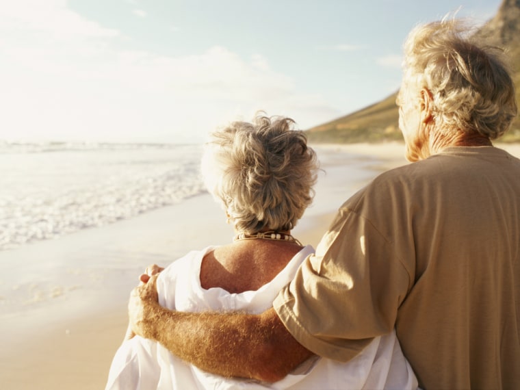 Senior couple embracing on beach, rear view