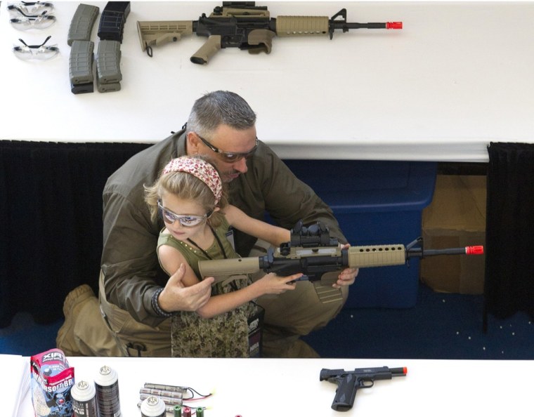 With a little help, a child shoots an Airsoft gun at a target during NRA Youth Day events at the National Rifle Association's 142 Annual Meetings and Exhibits in Houston on Sunday, May 5, 2013..