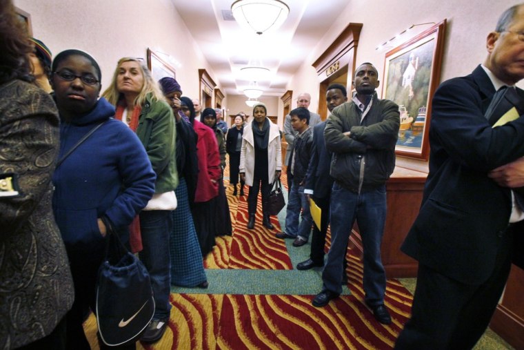 Job seekers line the hall at a job fair in SeaTac, Wash. The number of people requesting unemployment benefits last week dropped slightly, but the fou...