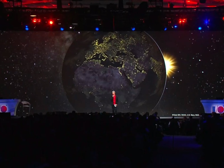 Google CEO Larry Page stands in front of a screen showing Google Earth
