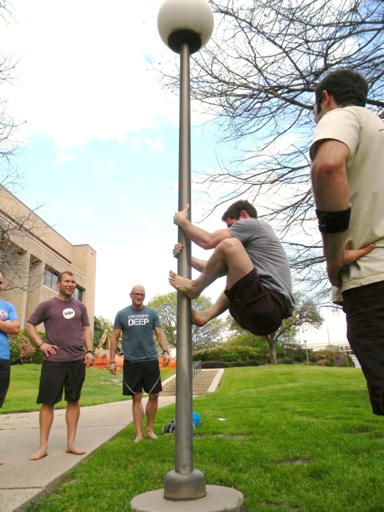 MovNat Workshop participants in Orlando practice a foot-pinch climb using a lamp post