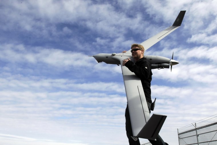 This photo taken March 26, 2013, shows flight test pilot Alex Gustafson carrying an InsituScanEagle unmanned aircraft in preparation for a flight in A...