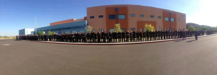 Phoenix police department officers line a school sidewalk as they wait for the arrival of 5-year-old Tatum Raetz, whose father was killed in the line of duty three days before her kindergarten graduation.