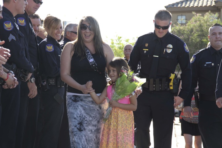 Stephanie Raetz and her 5-year-old daughter, Tatum, walk along a line of Phoenix police officers attending the girl's kindergarden graduation. Tatum's father was killed in the line of duty three days earlier.
