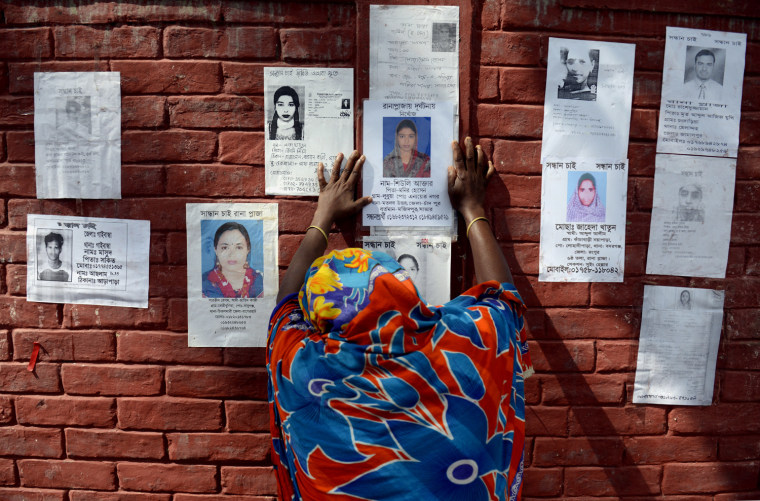 A woman cries as she sticks a poster of a a family member on the wall of a school turned makeshift morgue for Rana Plaza victims.