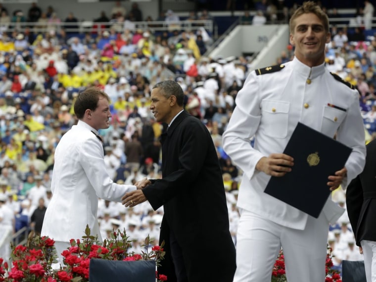 President Barack Obama congratulates a graduate as another one celebrates at the United States Naval Academy graduation ceremony in Annapolis, Md., Friday, May 24, 2013.