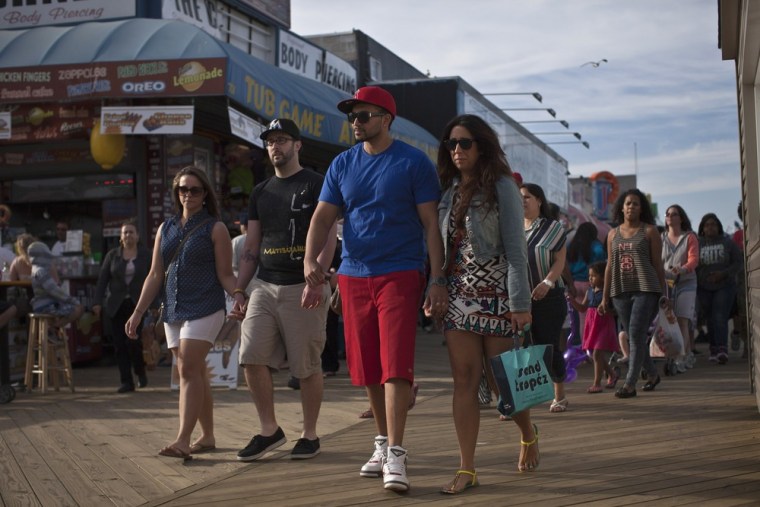 People walk along the broadwalk in Seaside Heights, New Jersey on the first weekend of New Jersey beaches re-opening to the public, Sunday.