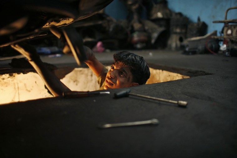 Mohammed Jundeya works underneath an automobile.