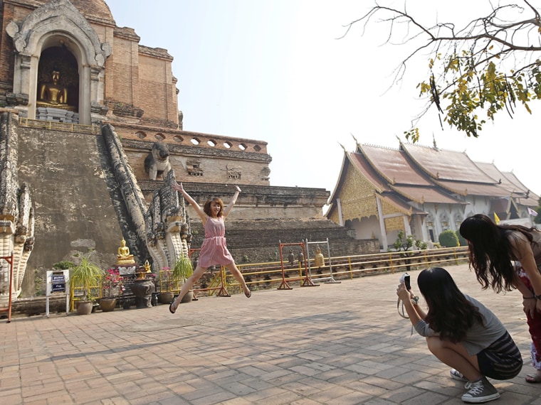 A Chinese tourist jumps as she poses for a souvenir photo at Wat Chedi Luang, an ancient Buddhist temple in northern Thailand.
