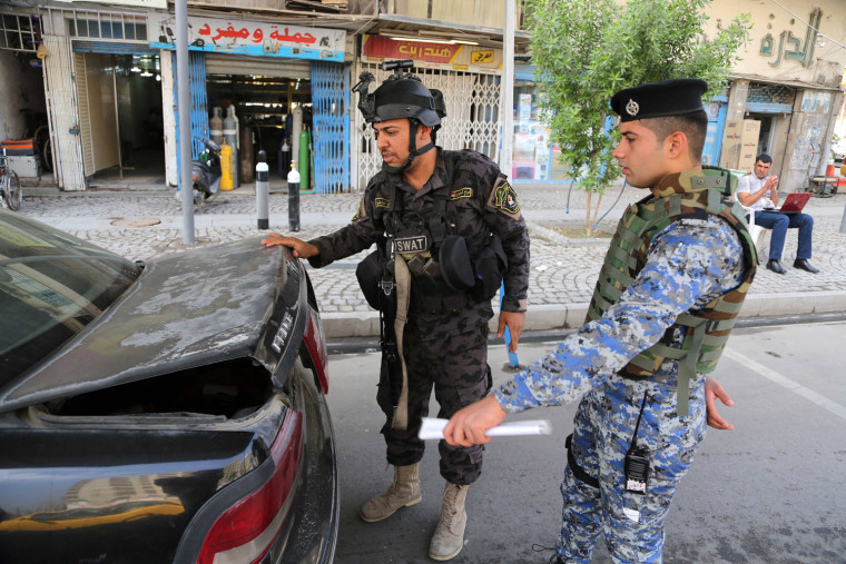 Iraqi policemen search a car at a checkpoint in central Baghdad on Thursday.