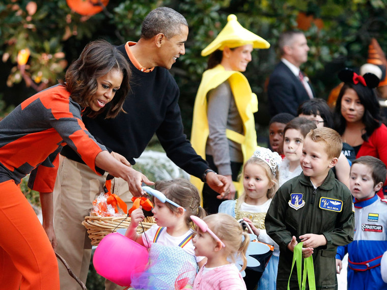 U.S. President Barack Obama (2nd L) and first lady Michelle Obama (L) give Halloween treats to visiting children at the White House in Washington, Oct...