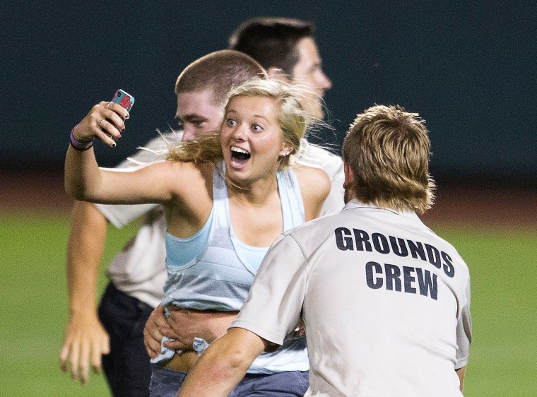 Unidentified female fan is grabbed by stadium security after she ran onto the field during the eighth inning of the 2013 Men's College World Series Fi...
