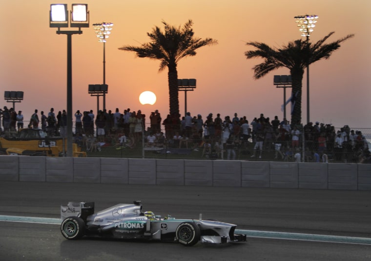 Mercedes driver Nico Rosberg of Germany steers his car during the Abu Dhabi Formula One Grand Prix at the Yas Marina racetrack in Abu Dhabi, United Arab Emirates, on Nov. 3, 2013. The moon crosses in front of the sun during a partial solar eclipse at background.