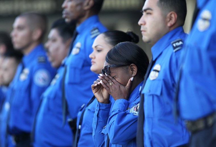 A TSA officer wipes her eyes as an honor guard escorts a U.S. National Honors Flag.