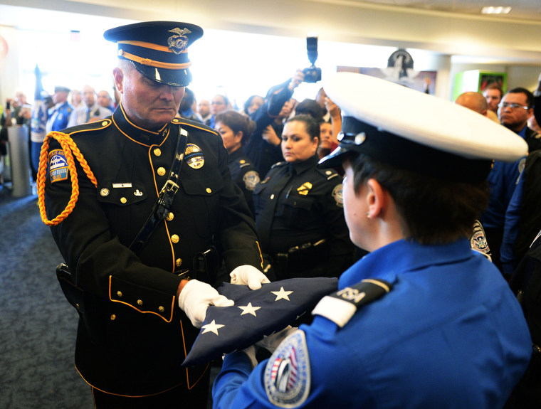 LAX Airport Police officer Tom Dye passes the U.S. Honor Flag to TSA honor guard Brandy Richards as it arrives at Los Angeles International Airport in memory of slain TSA agent Gerardo Hernandez.