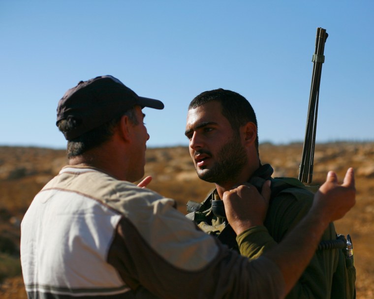 An Israeli soldier stops a Palestinian villager from getting to land near the Israeli settlement of Ma'on in the West Bank.