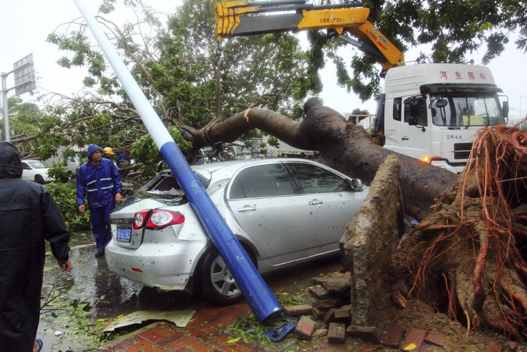 Workers remove a tree that fell on a car in the aftermath of Typhoon Haiyan in Sanya, southern China late Sunday.