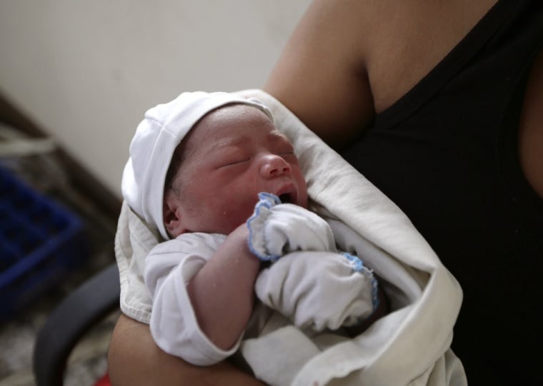 New-born baby Bea Joy is held by relative Michelle Satur after her mother Emily Ortega, 21, gave birth in an improvised clinic at Tacloban airport on Monday.
