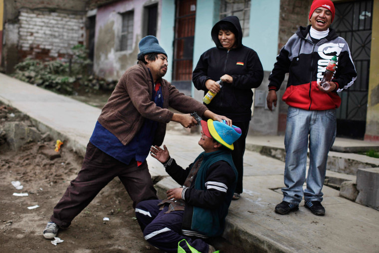 A man playfully points a toy gun at his friend's forehead, as the four unemployed and homeless Peruvians drink alcohol while passing the time in the Villa Maria del Triunfo, a neighborhood of Lima on Aug. 8.