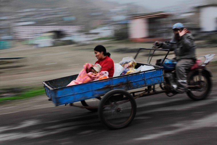 In this Aug. 12, 2013 photo, a man waves while transporting a woman with her daughter in a motorcycle cart in Lima, Peru. The dusty districts of Lima bulge with peasants whose high hopes for fortune are dashed by the grim reality of life on the margins. Most join the more than 60 percent of Peruvians in the informal economy. (AP Photo/Rodrigo Abd)