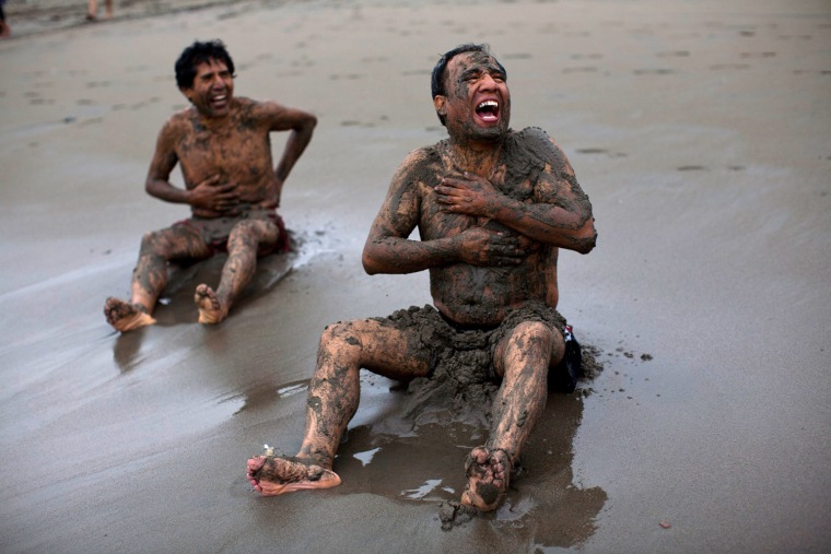 Men laugh as they smear wet sand on themselves while sitting on a public beach in the Chorrillos neighborhood of Lima, Peru, on July 13.
