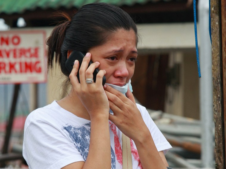 A woman cries as she talks on the phone to her relatives in the aftermath of Typhoon Haiyan on November 12, 2013 in Tacloban,