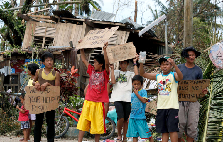 Children hold signs asking for help and food along the highway in Tabogon, Cebu Province, central Philippines Nov. 11, 2013.