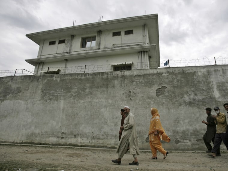 On May 5, 2011, four days after the raid that killed him, Pakistanis walk by the compound where al Qaeda leader Osama bin Laden was caught and killed in Abbottabad, Pakistan.