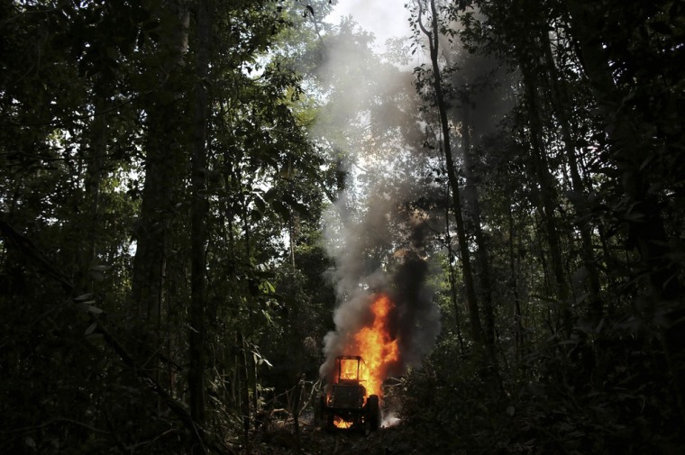 A tractor used to drag logs out of the rain forest burns after being destroyed by police on a raid to stop illegal logging in Jamanxim National Park, June 21, 2013.