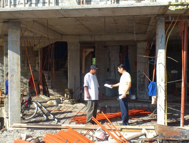 Architect Roberto Lilles, right, talks with the foreman at a construction site in Valle Verdi, a suburb of Manila.