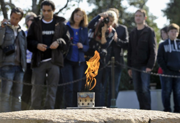 Visitors stand near the eternal flame at the grave site of President John F. Kennedy at Arlington National Cemetery on Oct. 29, 2013.