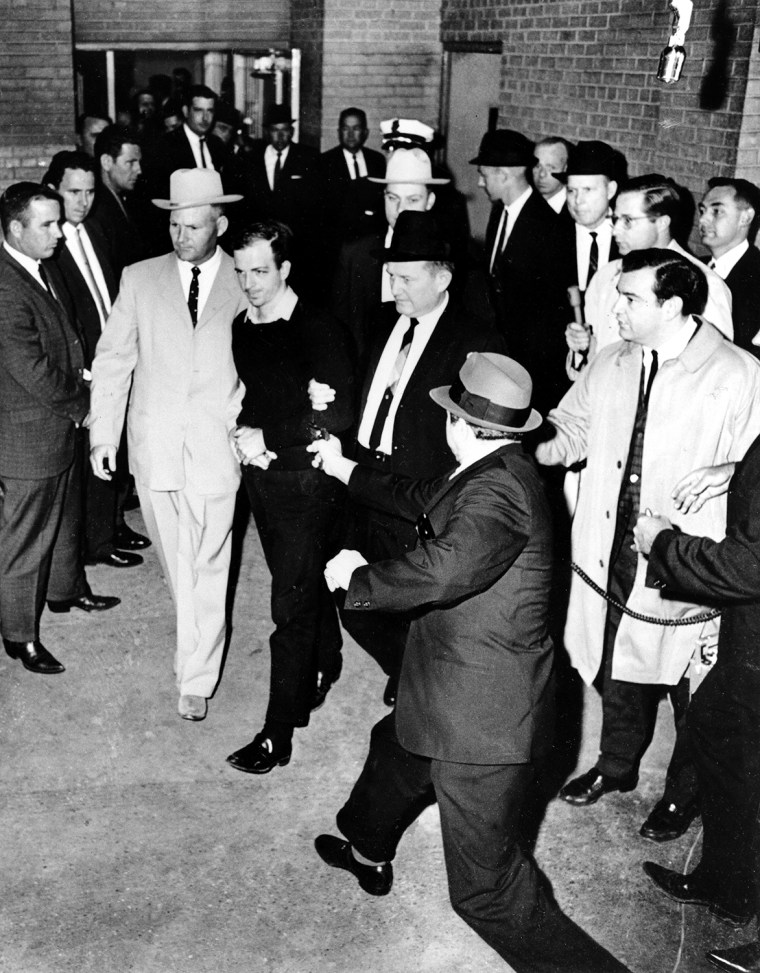 The accused assassin of President John F. Kennedy, Lee Harvey Oswald, center in handcuffs, is escorted to the Dallas city jail as nightclub owner Jack Ruby, foreground, approaches Oswald with a pointed revolver in the underground garage of the Dallas police headquarters, Texas, Nov. 24, 1963. Seconds later Ruby shot Oswald in the stomach.