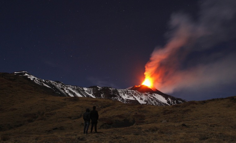 People watch Mount Etna, Europe's tallest and most active volcano, spewing lava as it erupts on Sunday.
