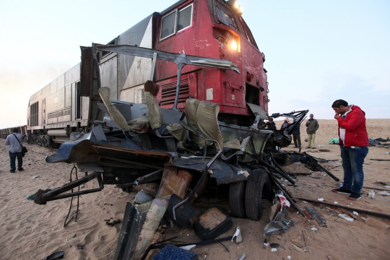 People inspect the wreckage on Monday after a train crash in the Giza neighborhood of Dahshour, south of Cairo.