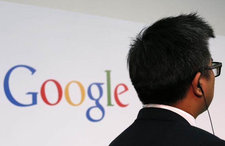 A man stands in front of a Google logo before a talk titled