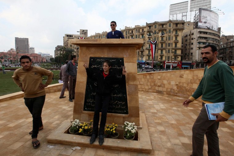 Egyptians pose next to a memorial commemorating those killed in the 2011 revolutionary unrest, at the center of Tahrir Square, in Cairo, Egypt, Tuesday.