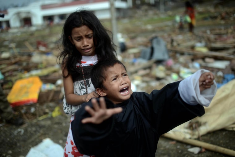 Two children cry as their mother tries to use a fridge to transport them to a neighboring island, in typhoon-ravaged Tacloban city on Saturday. Aid workers persuaded the woman not to embark on the perilous journey.