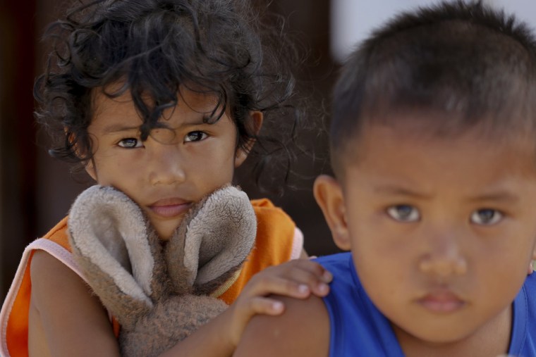 A 6-year-old girl and a 5-year-old boy hold soft toys in the town of Guiuan.
