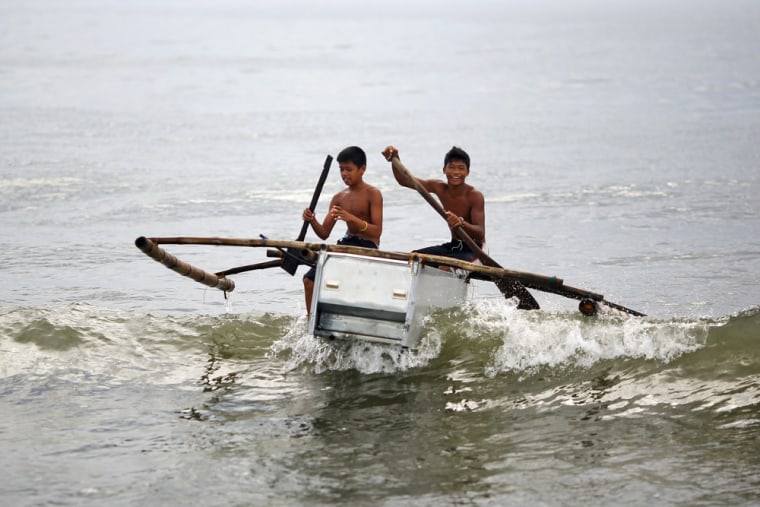 Boys maneuver their boat, made from a broken fridge and bamboo, to the beach. The first fridge boat was made by a fisherman whose children gave him the idea as they wanted to play in it.