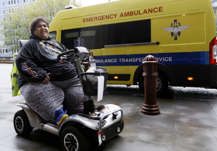Kevin Chenais sits in his mobility scooter on Wednesday in front of an ambulance in London. Kevin, who suffers from a medical condition, will travel by ambulance and ferry back to France.