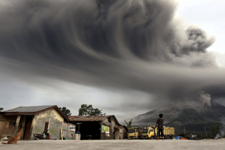 A woman looks on as Mount Sinabung spews ash, in Karo district, Indonesia's north Sumatra province, on Nov. 18. Mount Sinabung continued to spew volcanic ash throwing a plume five miles into the atmosphere on Monday as thousands of residents remained in temporary shelters fearful of more eruptions, according to local media.