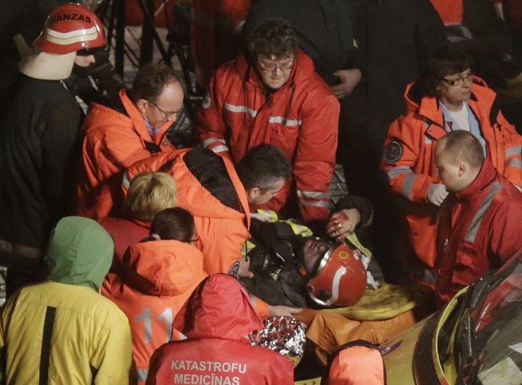 Paramedics inspect a firefighter on a stretcher after he was moved from the collapsed Maxima supermarket in Riga Nov. 21, 2013.