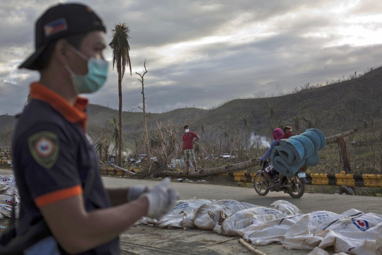 A firefighter stands near rows of Typhoon Haiyan victims in body bags on the roadside outside of Tacloban, Philippines, on Nov. 19.