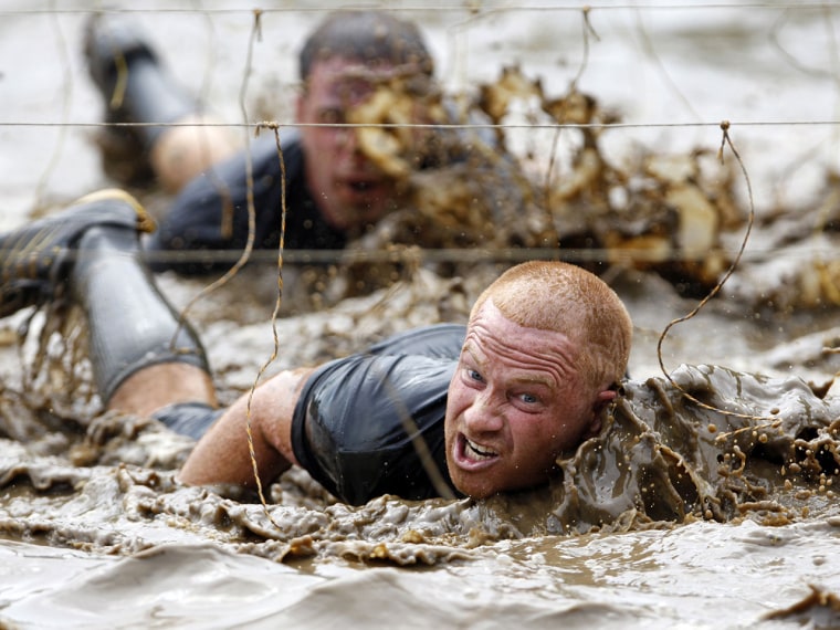 Competitors swim through mud underneath electrified wires on July 15, 2012, during the Tough Mudder at Mt. Snow in West Dover, Vt. The Tough Mudder is a nine-mile endurance event in which competitors run through a military-style obstacle course complete with mud, water and fire.