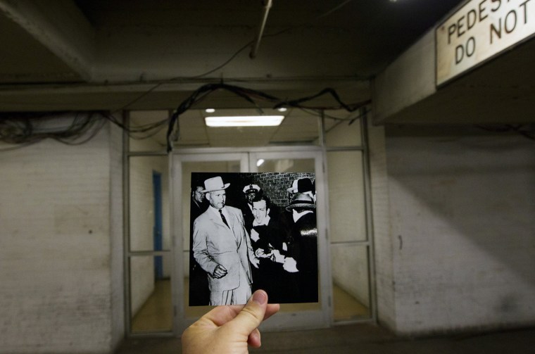 Lee Harvey Oswald, assassin of President John F. Kennedy, reacts as Dallas night club owner Jack Ruby, foreground, and shoots at him from point blank range in a corridor of Dallas Police Headquarters, juxtaposed with the current scene at the Dallas Police Headquarters, in Dallas.